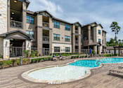 Thumbnail 11 of 28 - A large apartment complex with a pool in the middle of the courtyard.