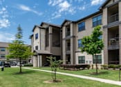 Thumbnail 26 of 28 - A sunny day at a residential complex with apartment buildings and green lawns.