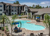 Thumbnail 10 of 28 - A large outdoor swimming pool surrounded by lounge chairs and trees.