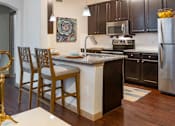 Thumbnail 9 of 28 - A kitchen with a white island and wooden chairs.