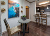 Thumbnail 4 of 28 - A kitchen with a table and chairs and a painting on the wall.
