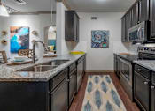 Thumbnail 3 of 28 - A kitchen with black appliances and a patterned rug on the floor.