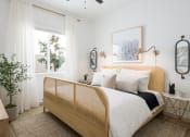 Thumbnail 5 of 18 - a bedroom with white walls and a wooden bed with white bedding
