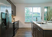 Thumbnail 16 of 33 - a kitchen with dark cabinets and a large window