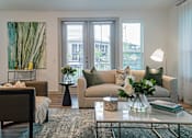 Thumbnail 7 of 33 - a living room with beige couches and a coffee table with a vase of flowers