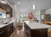 Thumbnail 1 of 36 - A modern kitchen with dark brown cabinets and a white countertop.