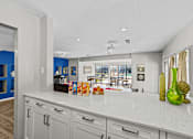 Thumbnail 17 of 17 - A kitchen with white cabinets and a white countertop with a green vase on it.