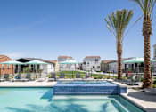 Thumbnail 16 of 19 - A swimming pool surrounded by palm trees and lounge chairs.