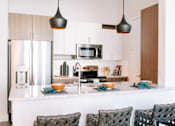 Thumbnail 1 of 22 - A modern kitchen with a white countertop and a refrigerator.