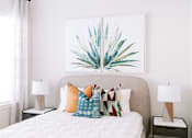 Thumbnail 6 of 22 - A bedroom with a bed, two lamps, and a painting of a plant.