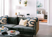 Thumbnail 3 of 22 - A living room with a grey couch and a glass table.