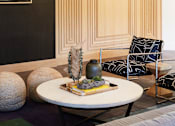 Thumbnail 14 of 22 - A modern living room with a round table and a chair with a black and white pattern.