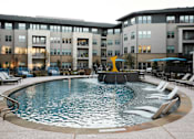 Thumbnail 7 of 22 - A round swimming pool with a waterfall in the middle of it.