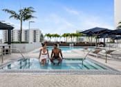 Thumbnail 4 of 76 - Two people are sitting in a pool on a sunny day.