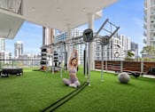 Thumbnail 38 of 76 - A woman exercising in a gym with a view of the city.