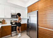 Thumbnail 50 of 76 - A woman is standing in a kitchen with a stove and refrigerator.