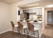 Thumbnail 28 of 44 - A kitchen with a white countertop and brown chairs.