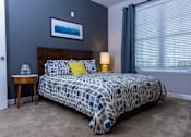 Thumbnail 5 of 14 - A bedroom with a bed, nightstand, and a painting on the wall.