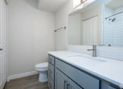 Thumbnail 30 of 44 - A white toilet sits in a bathroom with a white sink and a white door.