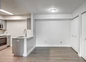 Thumbnail 9 of 44 - an empty kitchen and living room with white walls and wood floors