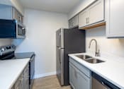 Thumbnail 22 of 44 - A kitchen with a black refrigerator and stainless steel appliances.