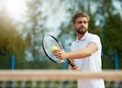 Thumbnail 4 of 7 - A man in a white shirt is holding a tennis racket and ball.