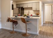 Thumbnail 20 of 44 - A kitchen with a white counter and two brown barstools.