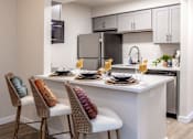 Thumbnail 27 of 44 - A kitchen with a white countertop and a black refrigerator.