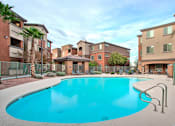 Thumbnail 1 of 14 - A swimming pool surrounded by a fence and buildings.