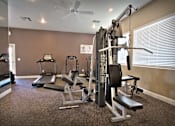 Thumbnail 9 of 16 - A home gym with a treadmill, elliptical trainer, and weightlifting equipment.
