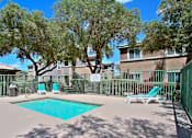 Thumbnail 2 of 16 - A pool surrounded by trees and chairs.