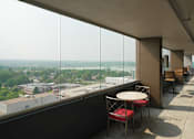 Thumbnail 12 of 50 - Enclosed exterior walkway with seating and Sloan's Lake in the distance at Denver Metro Village Apartments, Denver, CO, 80204