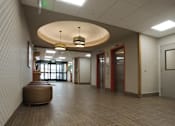 Thumbnail 50 of 50 - A hallway with a round light fixture and a bench at Denver Metro Village Apartments, Denver, 80204