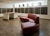 Thumbnail 18 of 50 - A red chair sits in front of a wall of black plaques at Denver Metro Village Apartments, Denver, CO