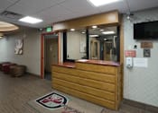 Thumbnail 21 of 50 - A reception area with a wooden desk and a rug with a compass design at Denver Metro Village Apartments, Colorado