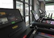 Thumbnail 24 of 50 - A treadmill with a screen showing a workout session at Denver Metro Village Apartments, Denver, CO, 80204