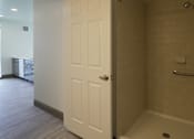 Thumbnail 37 of 50 - A white door is open to a bathroom with a walk-in shower at Denver Metro Village Apartments, Denver, 80204