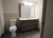 Thumbnail 47 of 50 - A bathroom with a toilet, sink, and mirror at Denver Metro Village Apartments, Denver, CO, 80204