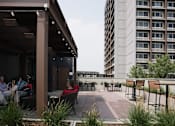 Thumbnail 8 of 50 - A group of people are sitting on a patio with a building in the background at Denver Metro Village Apartments, Denver, Colorado