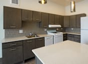 Thumbnail 34 of 50 - A kitchen with a white counter top and brown cabinets at Denver Metro Village Apartments, Denver, 80204