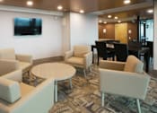 Thumbnail 38 of 50 - A living room with a couch, chairs, and a television at Denver Metro Village Apartments, Colorado, 80204