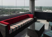 Thumbnail 13 of 50 - A red couch with a striped pattern sits in a room with a view of the city at Denver Metro Village Apartments, Denver, CO