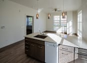 Thumbnail 41 of 50 - A modern kitchen with a white countertop and wooden cabinets at Denver Metro Village Apartments, Denver, Colorado