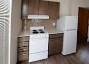 Thumbnail 44 of 50 - A white stove and refrigerator in a kitchen with brown cabinets at Denver Metro Village Apartments, Colorado