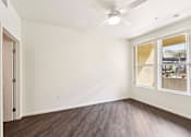 Thumbnail 11 of 42 - A room with a ceiling fan and a window overlooking a backyard.