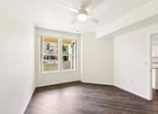 Thumbnail 7 of 42 - A room with a ceiling fan and a window showing a view of a building.