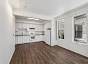 Thumbnail 29 of 42 - A kitchen with white cabinets and a wooden floor.
