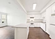 Thumbnail 33 of 42 - A white kitchen with wood floors and white appliances.