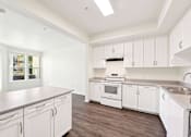 Thumbnail 24 of 42 - A kitchen with white cabinets and a stove top oven.