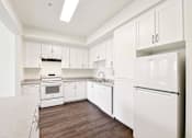 Thumbnail 25 of 42 - A white kitchen with a refrigerator on the right.